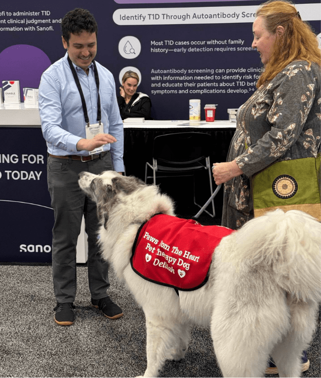 attendee meeting therapy dog in exhibit hall with the dog's handler
