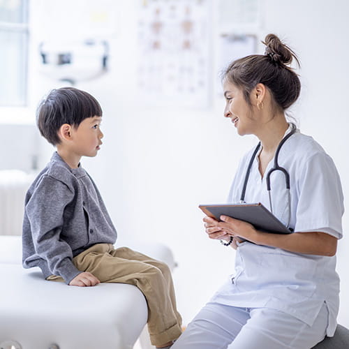 Clinician talking to a pediatric patient while holding a tablet
