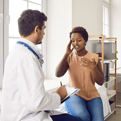 A woman discusses her migraine symptoms with her doctor.